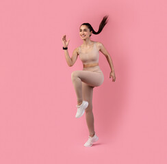 Fototapeta na wymiar Smiling Young Woman Jumping And Exercising Isolated On Pink Background