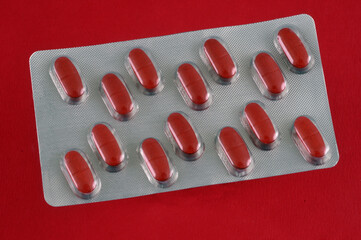 Blister de gélules rouges en gros plan sur fond rouge