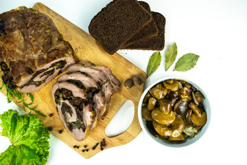 Baked meatloaf pork with prunes and mushrooms cut into pieces on a cutting board.