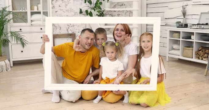 large happy family holding picture frame and smiling. the whole family is wearing white and yellow T-shirts. parents and children have a great time together