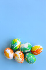 Top view of multicolored Easter eggs on a blue background. Happy Easter card. Dyed Easter eggs. Copy space for your text. Flat lay style. Top view. 