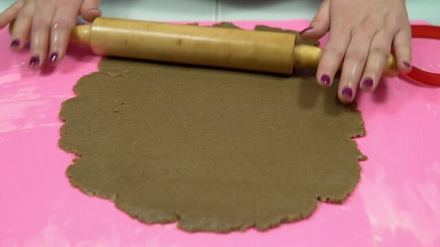 A woman rolls out the dough with a rolling pin. Making baking dough