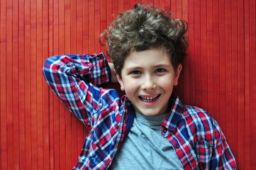 Smiling little boy with raised hands on red wooden floor
