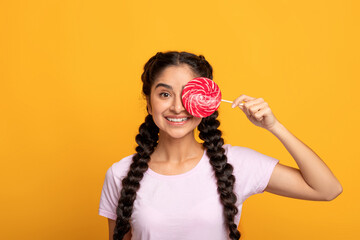 Indian lady holding lollipop, covering one eye with candy