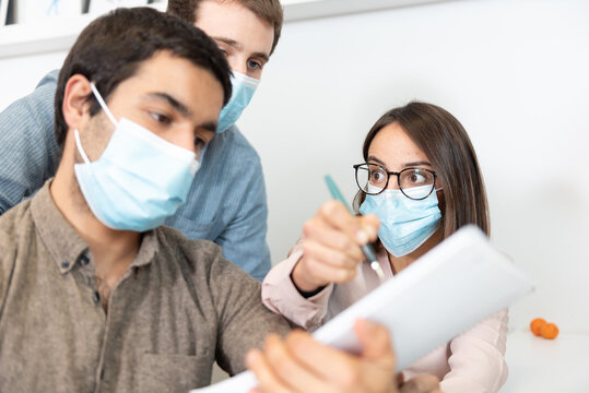 Coworkers wearing face masks contrasting opinions at the workplace. Working in the office during Coronavirus pandemic concept.