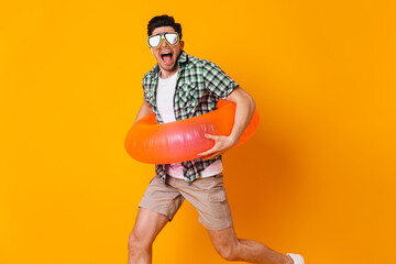 Fototapeta na wymiar Guy in diving mask and inflatable circle runs on orange background