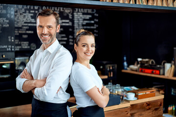 Small business owners standing together at restaurant cafe looking at camera