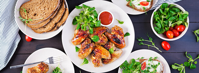 Grilled chicken wings. Baked chicken wings on wooden table. Table setting. Top view, banner, overhead