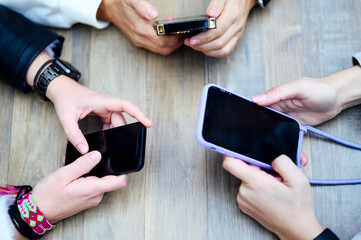 Close up group of European girls holding a smartphone or cell phone with black screen. Lifestyle freelance work and marketing concept