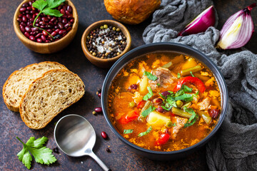 Homemade Meat Tomato soup with beef and bean stew, vegetables on a stone tabletop.