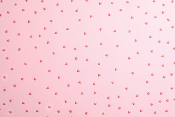 Tasty bright heart shaped sprinkles on pink background, flat lay