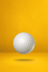 White golf ball on a yellow studio background