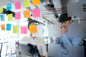 Fototapeta premium Businessman and businesswomen stand and watch the posed poses written on the glass