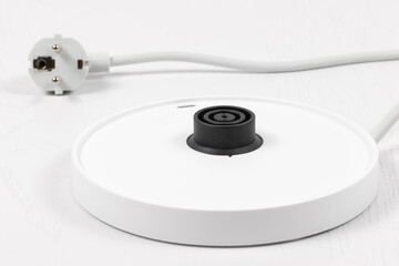 white teapot stand with wire and electric plug on white wooden table