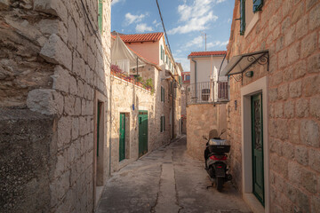 A lone scooter is parked along a quiet backstreet in this quaint neighbourhood scene from the charming old town of Split, Croatia on a warm sunny afternoon.