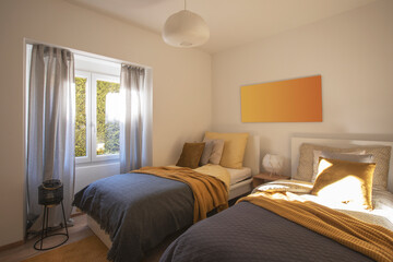Modern bedroom with two singles beds with clean bed sheets and large pillow above. White wall