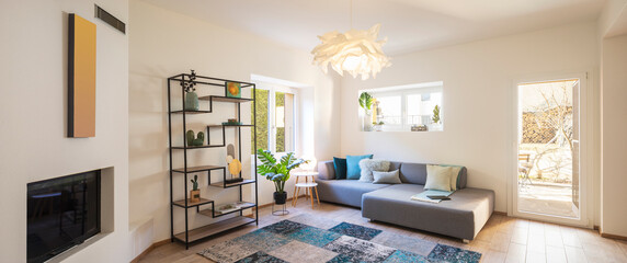 Panorama of wide modern living room with design sofa and large pillows above. Design library and small fireplace