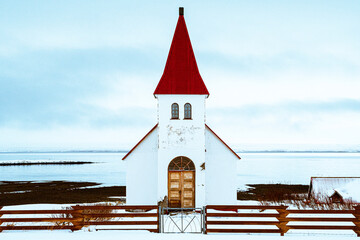 Iglesia antigua de madera de estilo nórdico, con paredes blancas y techo rojo, tras una valla de...