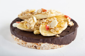 Puffed exploded wheat grains with chocolate glaze with muesli and cut banana slices on a light wooden background. Close-up