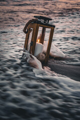 Laterne mit Kerze in der Wellen Brandung am Strand Hochformat