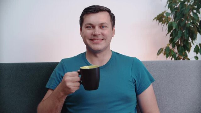 The man drinks a drink from a mug.