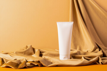 Group of cosmetics tubes bottles abstract podium yellow background draped cloth.