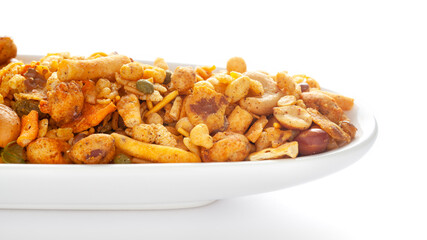 Pile of Indian spicy snacks (Namkeen) - 'All in one' in a white  ceramic oval bowl, made with fried peanut, corn flakes, sweet pea, pulses, cashew nuts, etc. side view, 
