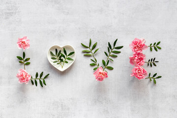 Word Love made of pink flowers and green leaves, overhead view