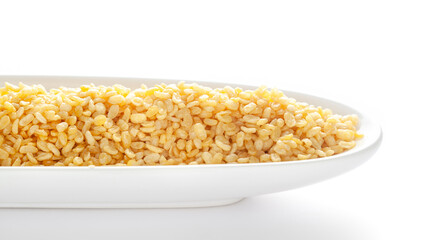 Crunchy Moong Dal in a white oval bowl, made with roasted Mung bean. Pile of Indian spicy snacks (Namkeen), under backlight, side view, against the white background.