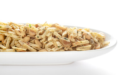 Aloo Mixture in a white ceramic oval bowl made with potatoes peanuts raisins etc. Pile of Indian spicy snacks (Namkeen)  under backlight side view against the white background.