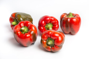 a group of Bulgarian sweet peppers on a white background, with shadows. studio photo, isolate, peppers washed. Peppers are red, with green spots