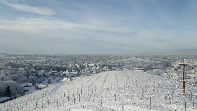 Drone Flying Above Snowy Vineyard Hill With Cross Standing On Top In Offenburg, Germany. aerial
