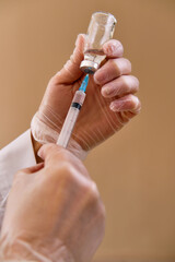 Close up female nurse wear protective gloves holding syringe and vaccine vial dose against pandemic...