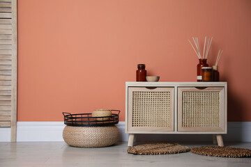 Wooden commode near coral wall in room. Interior design