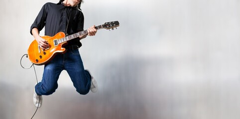 Male guitarist playing music and jump