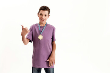 Fototapeta premium Happy teenaged disabled boy with cerebral palsy wearing gold medal, smiling and showing thumbs up at camera, standing isolated over white background