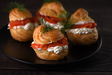 Profiteroles stuffed with cream cheese and salmon, decorated with a sprig of dill. Close-up 