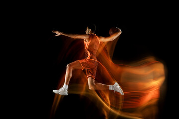 Jumping. Young arabian muscular basketball player in action, motion isolated on black background in mixed light. Concept of sport, movement, energy and dynamic, healthy lifestyle. Training, practicing
