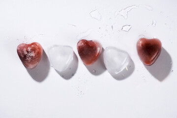 Heart shaped ice with strawberries against white background.
