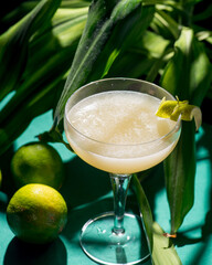 yellow tropical cocktail on a background of foliage, shadows from the sun. Green background