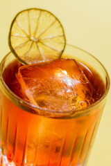 cocktail in an old fashion glass on a background of foliage, shadows from the sun. Yellow background