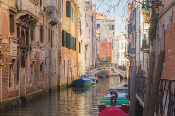 Sunshine and boats along a quiet colourful canal in Venice, Italy.