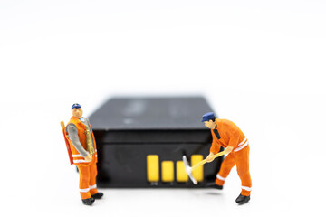 Miniature worker digging on battery. Concept of search for renewable energy or new energy.
