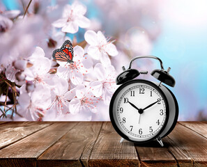 Black alarm clock on wooden table, space for text. Daylight saving time (Spring forward)