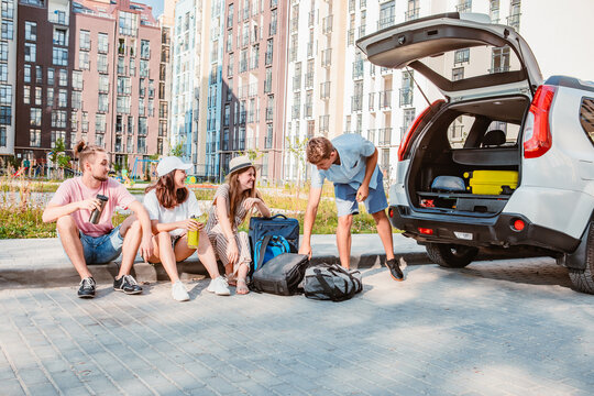 friends load car trunk with baggage