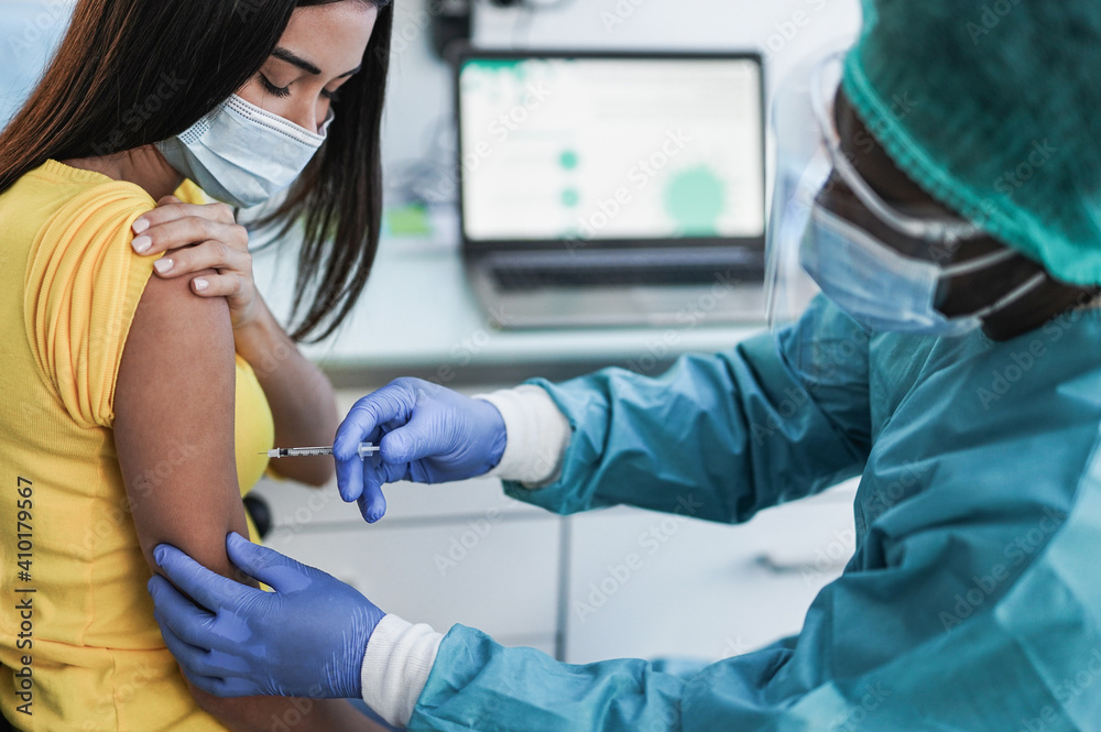 Wall mural african doctor with syringe injecting covid-19 vaccine on young woman patient - health care mediacal