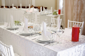 Table setting with sparkling wineglasses, plate with white napkin and cutlery on table, copy space. Place set at wedding reception. Table served for wedding banquet in restaurant