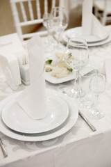 Table setting with sparkling wineglasses, plate with white napkin and cutlery on table, copy space. Place set at wedding reception. Table served for wedding banquet in restaurant