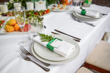 Table setting with sparkling wineglasses, plate with white napkin and cutlery on table, copy space. Place set at wedding reception. Table served for wedding banquet in restaurant