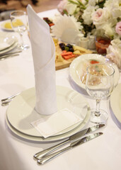 Table setting with sparkling wineglasses, plate with white napkin and cutlery on table, copy space. Place set at wedding reception. Table served for wedding banquet in restaurant